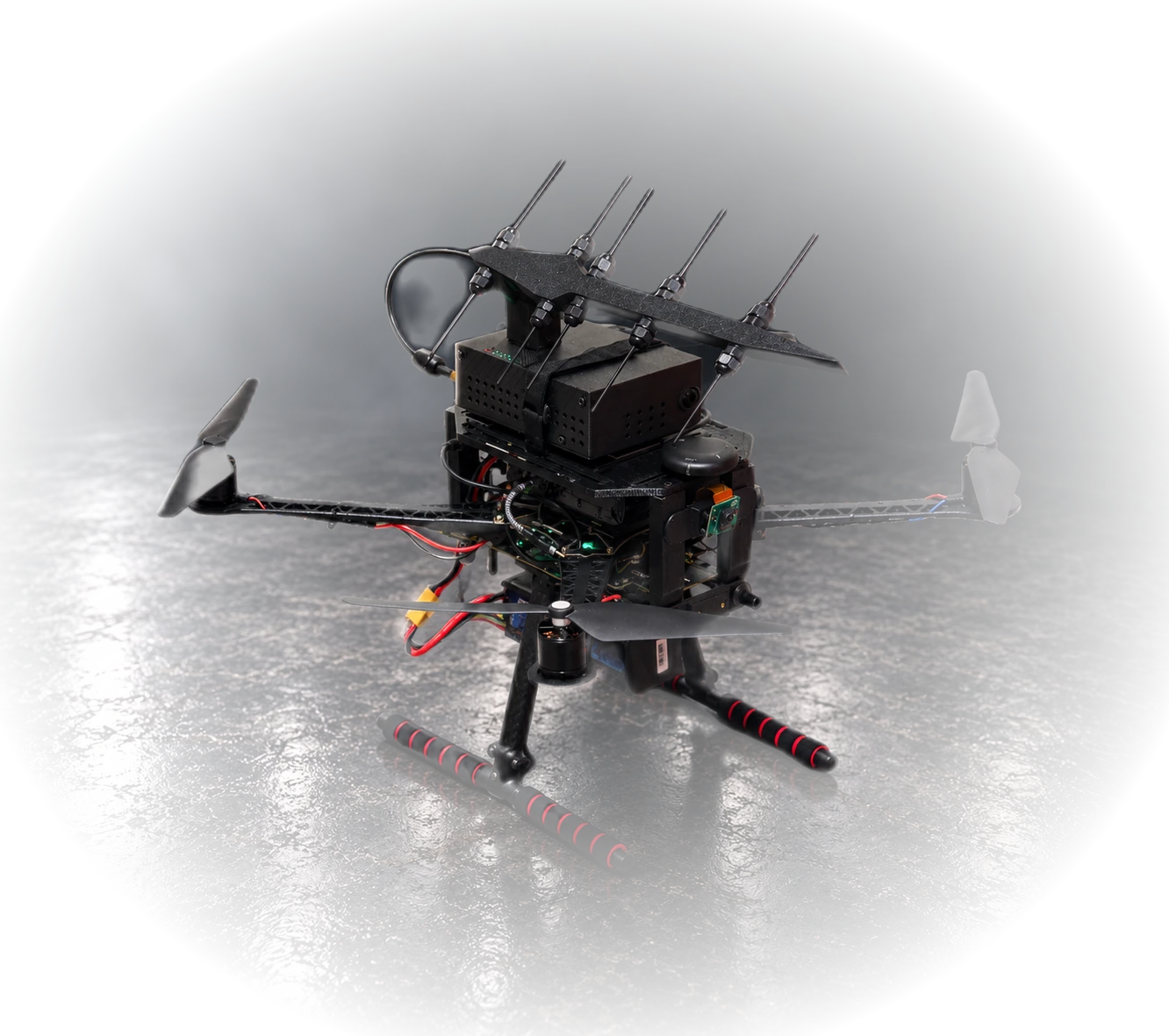 The Lykos payload mounted on a rugged quadcopter airframe: a Yagi-style directional antenna array above a hardened enclosure with an integrated camera, flanked by a GPS antenna and carbon-fiber landing legs.